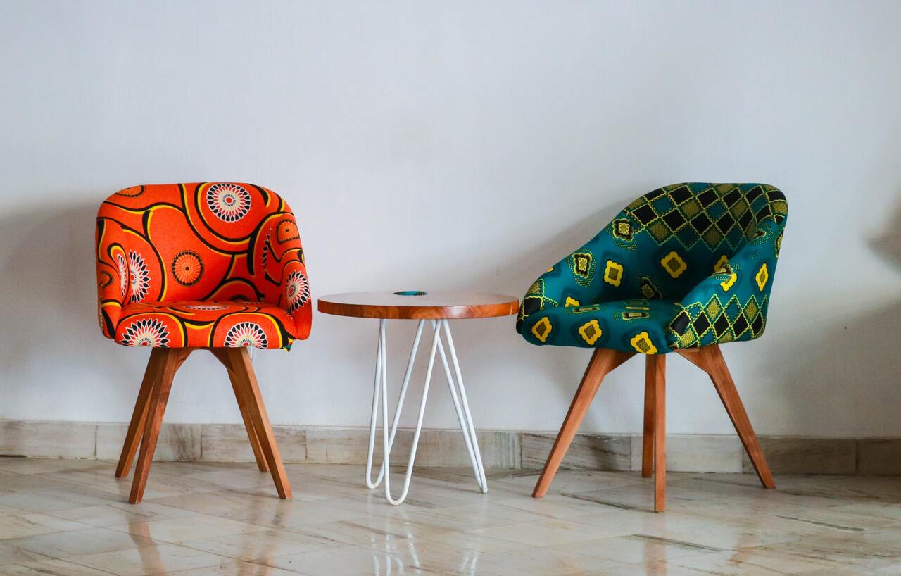 Designerskie, tapicerowane krzesła o różnobarwnej kolorystyce, z drewnianymi nogami.